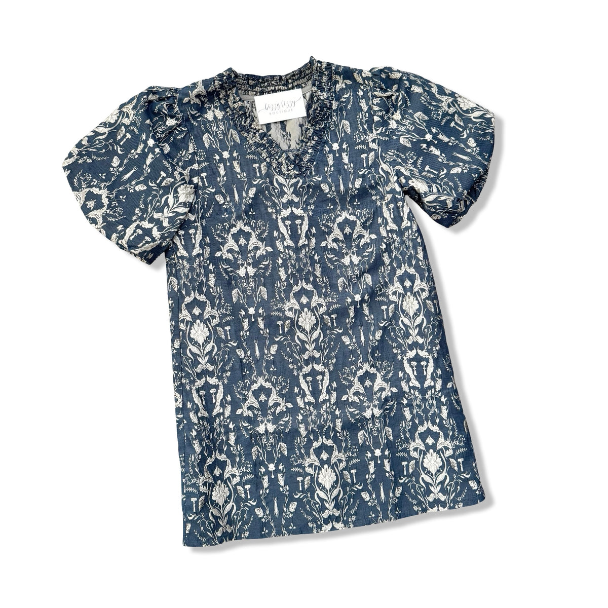A short-sleeve V-neck blouse with a blue and white ikat pattern, featuring puff sleeves and a small button placket, shown flat on a white background.