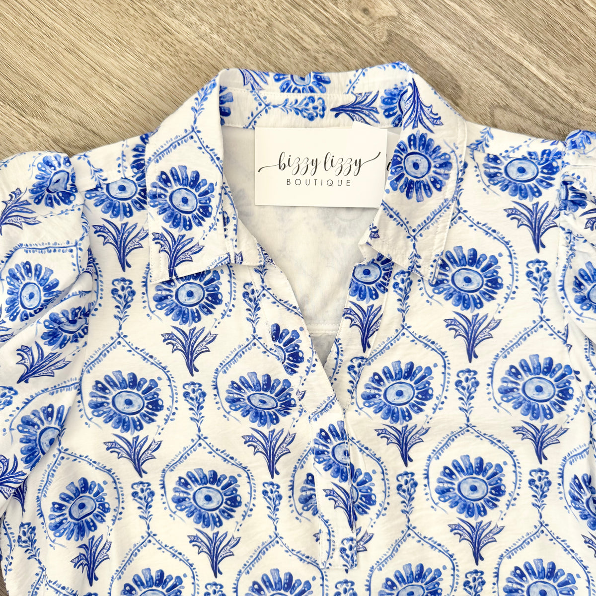 Blue and white patterned dress with a visible brand tag on a wooden surface