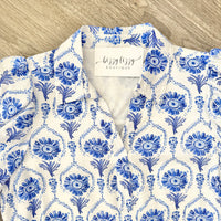 Blue and white patterned dress with a visible brand tag on a wooden surface