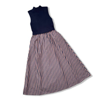 A sleeveless dress with a solid navy blue mock-neck bodice and a full skirt featuring vertical stripes in navy blue, and brown, shown on a white background.