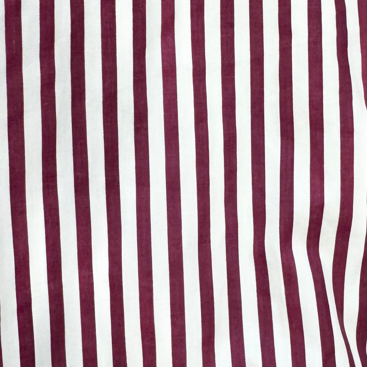 A close-up of a striped fabric with alternating vertical stripes of deep burgundy and white.