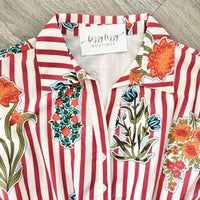Striped shirt with floral patches and 'Bizzy Lizzy Boutique' tag on a wooden surface