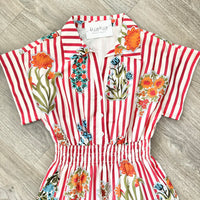 Red and white striped romper with floral patterns on a wooden floor