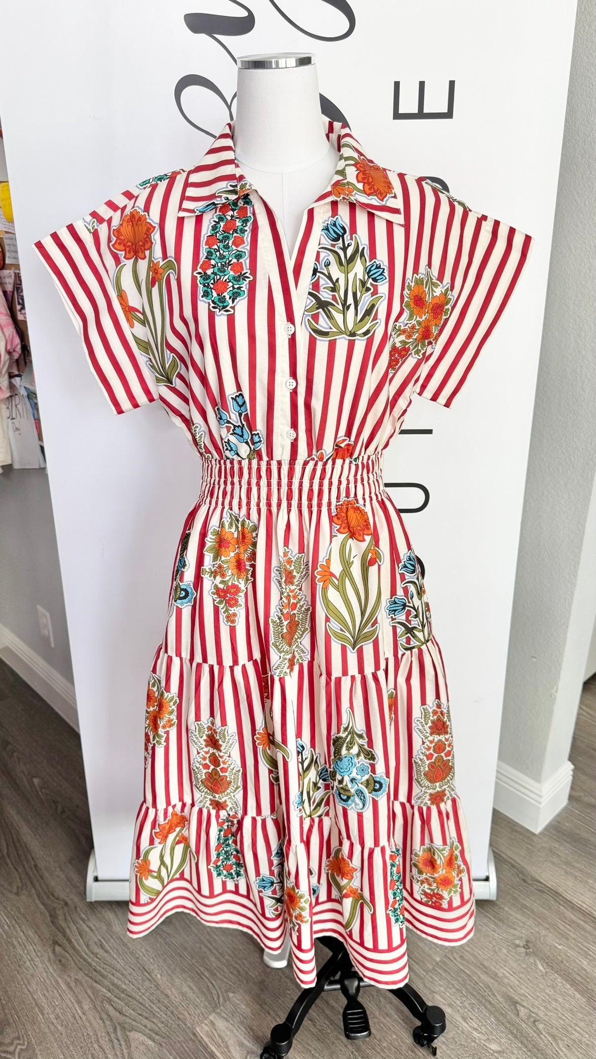 Red and white striped dress with floral patterns on a mannequin against a white background.
