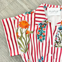 Striped shirt with floral designs on a wooden surface, featuring the brand 'bizzy lizzy'.