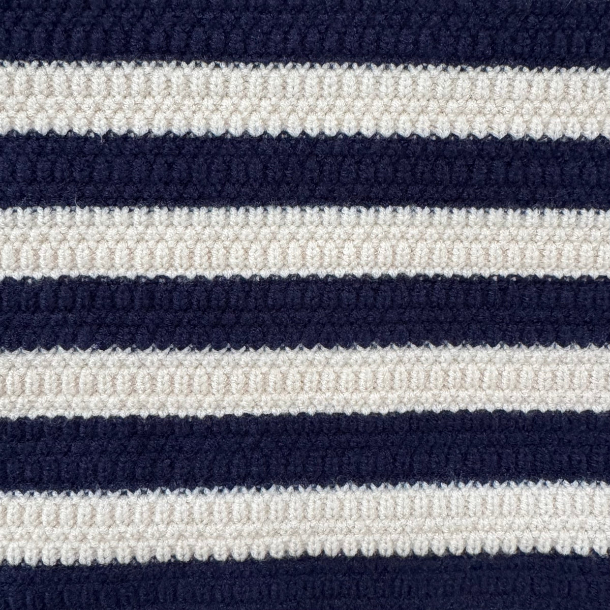 Close-up of a textured knit fabric with horizontal navy blue and off-white stripes.