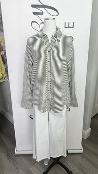 A long-sleeve button-up shirt with Dark blue and cream vertical stripes, styled on a white mannequin torso with white wide-leg pants against a white branded backdrop.