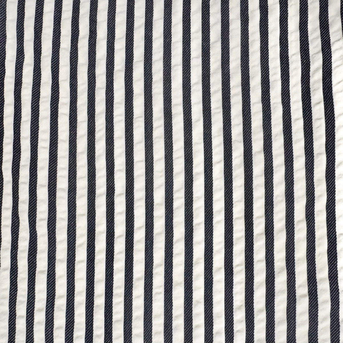 A close-up of a fabric pattern featuring vertical navy blue and off-white stripes.