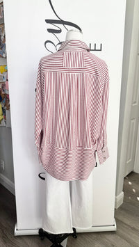 A pink and white vertically striped button-down shirt displayed on a white mannequin torso, paired with white wide-leg pants, set against a white clothing display stand.