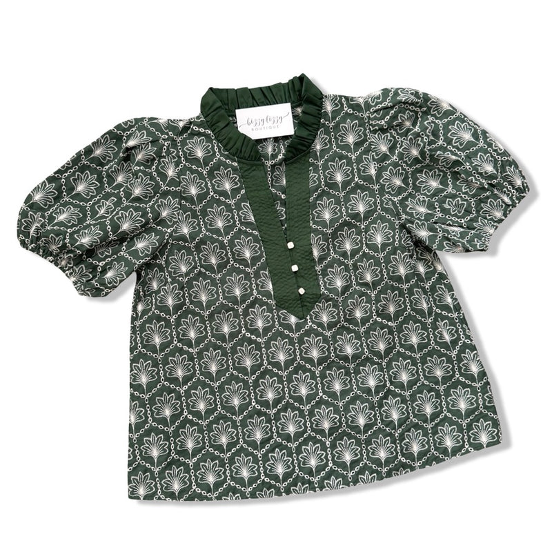 A dark green short-sleeve blouse with a white geometric pattern, featuring a ruffled collar, buttoned placket, and puffed sleeves, laid flat on a white background.