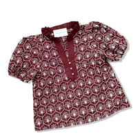 A women's short-sleeve blouse by Mignon, featuring a deep burgundy base with a repeating white floral pattern and a solid burgundy ruffled collar and button placket.