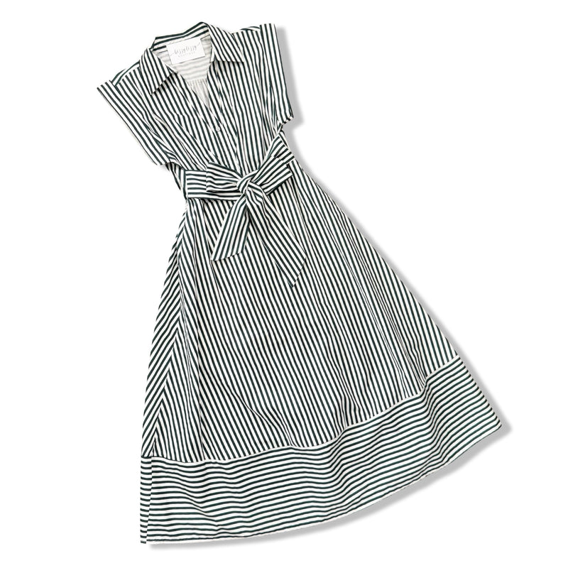 A sleeveless collared dress with vertical black and white stripes, featuring a tie waist and a tiered skirt, shown on a plain white background.
