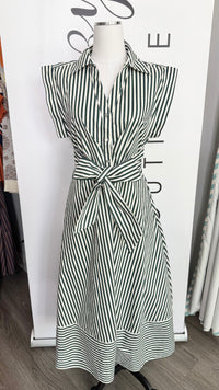 A sleeveless collared dress with a black and white striped pattern, featuring a self-tie waist belt, displayed on a mannequin in front of a white boutique backdrop.