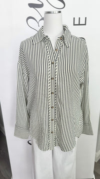 A long-sleeve button-up shirt with vertical black and white stripes, displayed on a white mannequin torso.