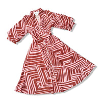 A long-sleeve wrap dress with a pink and brown geometric maze-like pattern, shown on a clean white background.