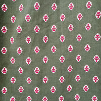 A close-up of a fabric pattern featuring a repeating motif of small pink floral or lotus-like shapes outlined in white, set against an olive green background.