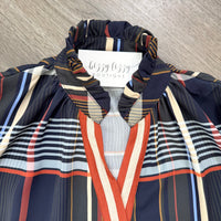 A close-up of a plaid and striped blouse from Bizzy Lizzy Boutique, featuring a navy blue base with red, beige, and light blue stripes, laid flat on a gray wood-textured surface.
