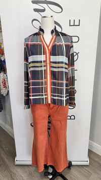 A two-piece clothing set displayed on a mannequin, featuring a long-sleeve button-up plaid shirt in navy, orange, white, and gray, paired with matching orange wide-leg pants.