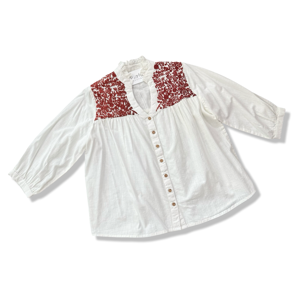 White blouse with red floral embroidery on a white background