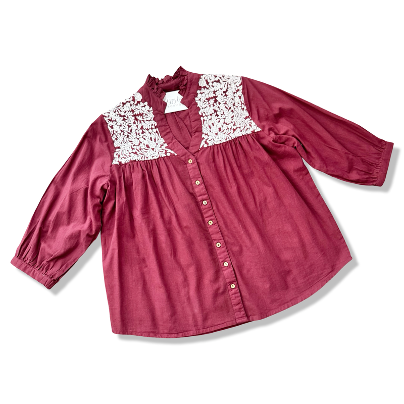 Maroon blouse with white lace details on a white background