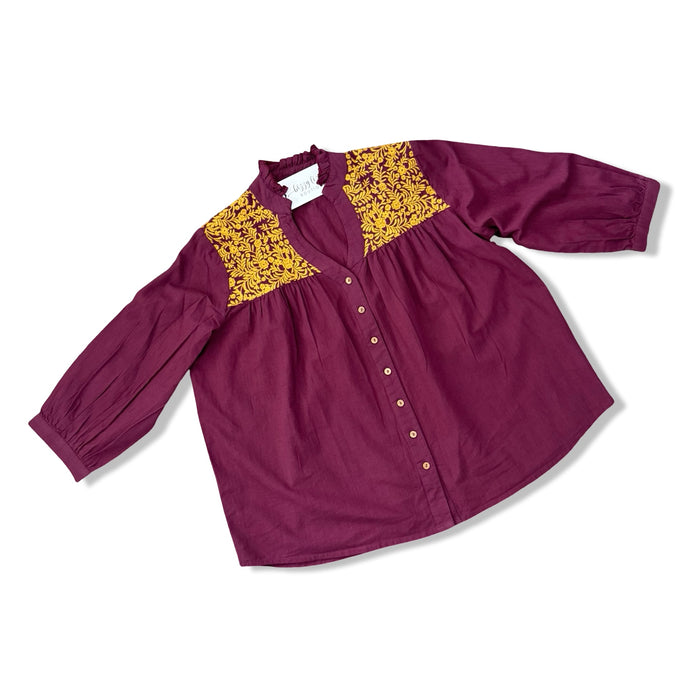 Maroon blouse with gold embroidery details on a white background