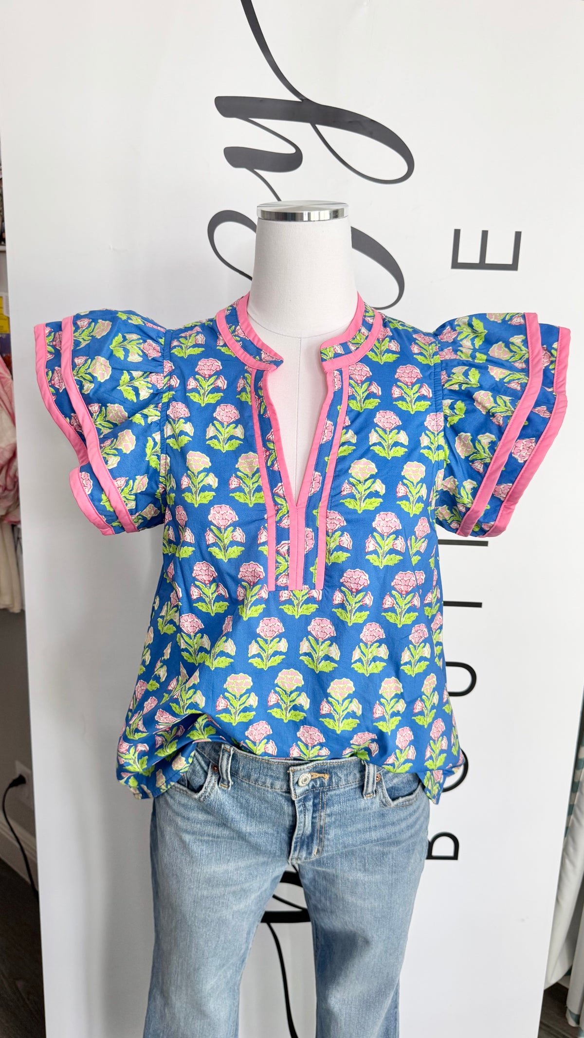 Mannequin wearing a blue floral blouse with pink accents on a white background