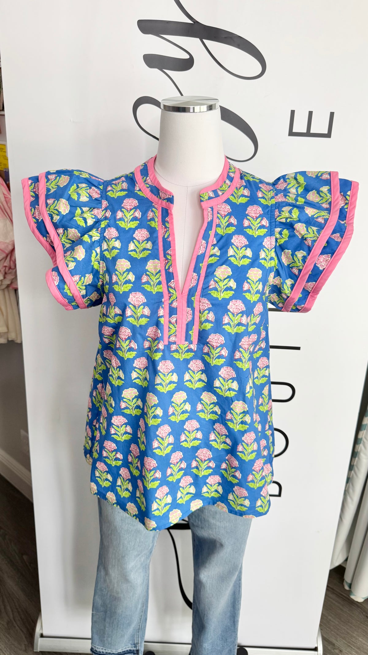 Blue floral-patterned top on a mannequin against a white background with black text.