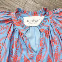 Blue and orange patterned top with a tag from Lizzy Lizzy Boutique on a wooden surface.