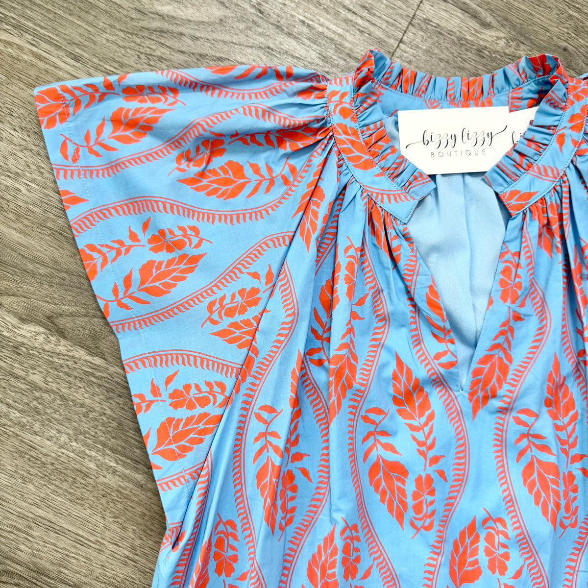 Blue and orange patterned dress with a brand tag on a wooden surface