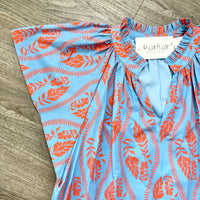 Blue and orange patterned dress with a brand tag on a wooden surface
