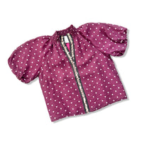 A maroon crinkled cotton top with white polka dots, featuring puff sleeves and a decorative patterned trim along the front zipper.