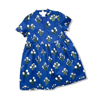 A short-sleeve blue dress with a white and green floral print, featuring a gathered waist and a V-neckline, shown flat on a white background.