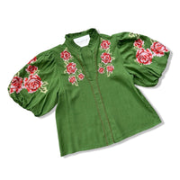 A green linen blouse with red and pink floral embroidery on the chest and sleeves, featuring puff sleeves and a high collar, shown on a white background.