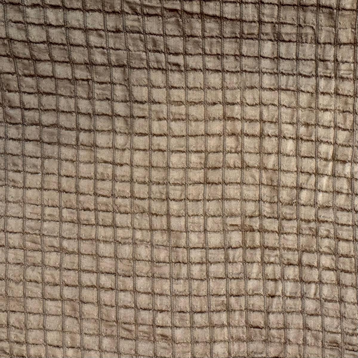 A close-up of a textured fabric with a grid-like woven pattern in warm taupe and brown tones.