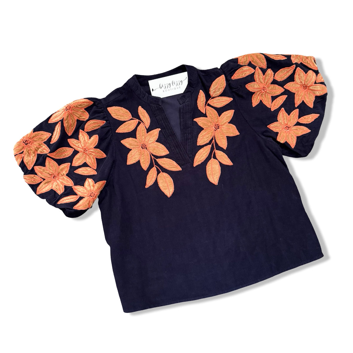A navy blue short-sleeve blouse with voluminous puff sleeves and large orange floral embroidery and applique on the shoulders and chest, displayed on a white background.