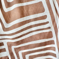 A close-up of a textile with a geometric pattern of wavy tan and off-white stripes.