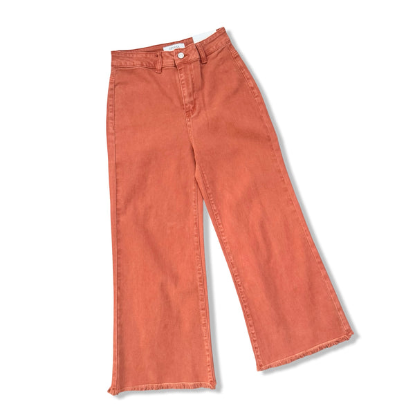 A pair of wide-leg cropped jeans in a washed terracotta or rust orange color, laid flat on a white background.